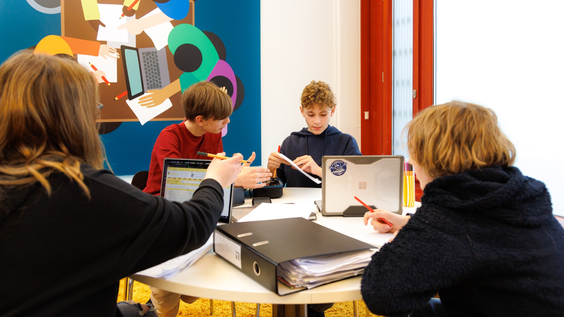 Kinder sitzen an einem Tisch und lernen miteinander am ipso! Haus des Lernens.