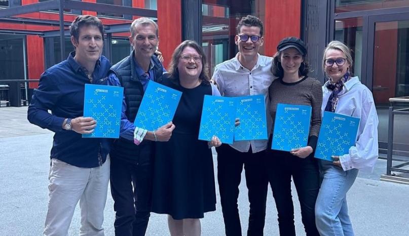 Foto einer Gruppe. Alle mit Zertifikatsmappen in der Hand.